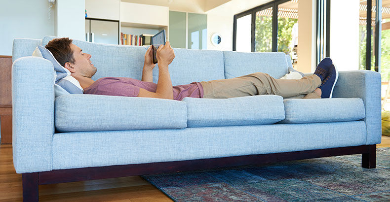 A student reading on a sofa in a bright apartment